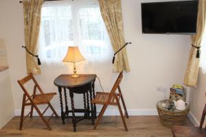 a room with a table and two chairs and a lamp at Two Hoots Chalet in Mundesley