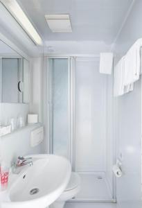 a white bathroom with a shower and a sink at Hotel Moerser Hof in Moers