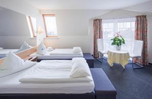Hotel Moerser Hof في مورس: غرفه بالفندق ثلاث اسره وطاولة وكراسي