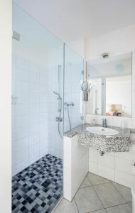 ein weißes Bad mit einem Waschbecken und einer Dusche in der Unterkunft Hotel Moerser Hof in Moers