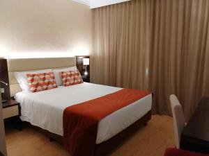a bedroom with a large bed with orange pillows at Hotel Monaco in Faro
