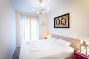 a bedroom with a white bed and a chandelier at AZ El Balcón de Cesar Augusto in Zaragoza