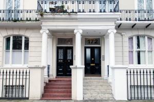 a white house with a black door and stairs at Italianflat - Holland Park in London