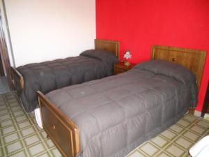 2 camas en una habitación con una pared roja en Albergo Maria Cristina, en Esperia