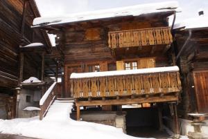 a wooden cabin with a balcony in the snow at Chalet Michel in Bruson