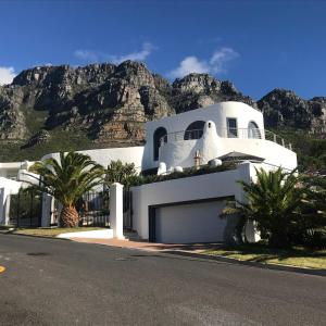 ein weißes Haus mit einem Berg im Hintergrund in der Unterkunft Four Uitsig Camps Bay in Kapstadt