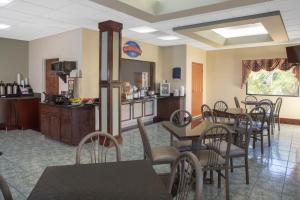 a dining room with tables and chairs and a kitchen at Baymont by Wyndham Midway Tallahassee in Midway