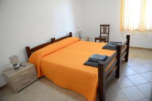 SerradifalcoにあるSicily Bike di Fina Rosarioのベッドルーム1室(オレンジのシーツと椅子付きのベッド1台付)
