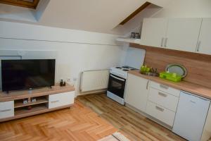 una cucina con armadi bianchi e una TV a schermo piatto di Apartman MAŠA a Banja Luka