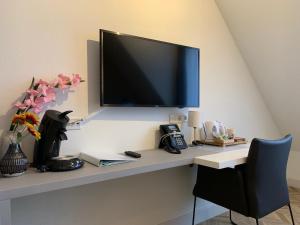 a desk with a flat screen tv on a wall at Hotel In den Brouwery in Domburg