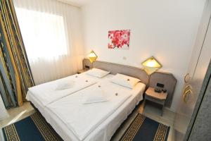 a bedroom with a large white bed with two lamps at Apartments Villa Ana in Cavtat