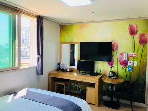 平沢市にあるHotel Joy near Camp Humphresのベッドとテレビ付きの机のある寝室
