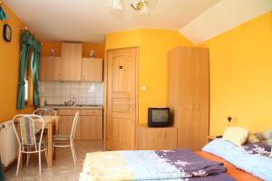 a bedroom with a bed and a kitchen with yellow walls at Bo-Ni Vendégház in Fertőd