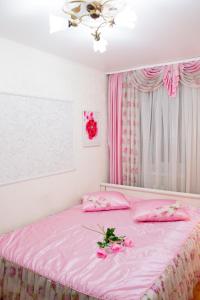 ヨシュカル・オラにあるулица Кирова дом15のピンクのシーツと花が飾られたピンクのベッド