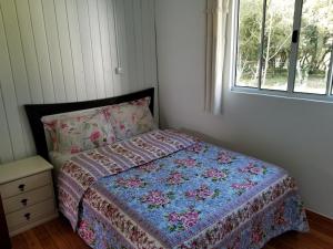 ein Schlafzimmer mit einem Bett mit einer Decke und einem Fenster in der Unterkunft Casa de Campo Passo do Tatu in Urupema