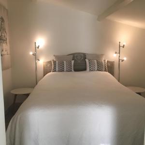 - une chambre avec un grand lit blanc et 2 tables dans l'établissement L' Esmerand, à Cotignac