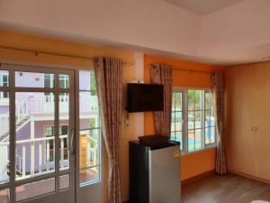Pokój z lodówką i balkonem z oknami. w obiekcie Bunny Hill Resort w mieście Chon Buri