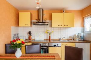 a kitchen with yellow cabinets and a table with a vase of flowers at Ferienhaus Seegras in Trassenheide