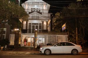 une voiture blanche garée devant une maison la nuit dans l'établissement Tuyet Suong Villa Hotel, à Quảng Ngãi