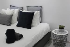 a bed with black and white pillows and a side table at Olosuites in Limassol