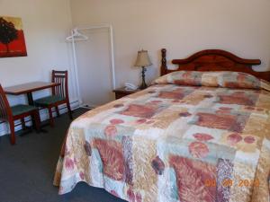 a bedroom with a bed and a desk and a table with chairs at Mountain Springs Motel & RV Park in Barrière