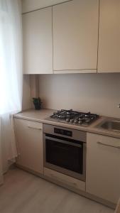 a kitchen with a stove and white cabinets at Lieporių Apartamentai in Šiauliai