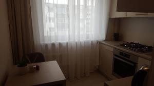 a kitchen with a stove and a window with curtains at Lieporių Apartamentai in Šiauliai