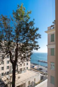 ein Baum vor einem Gebäude und dem Meer in der Unterkunft YouRelais Pergolesi in Neapel