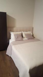 un grande letto con lenzuola bianche e cuscini rosa di Apartamentai Dainų II a Šiauliai
