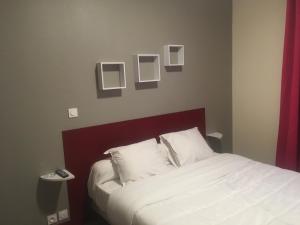 a bedroom with a bed with white sheets and pictures on the wall at HOTEL DE STRASBOURG in Aulnay-sous-Bois