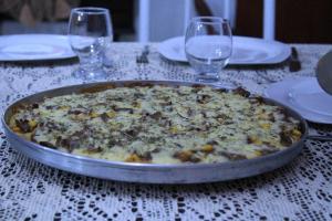 a pizza in a pan on a table with wine glasses at Pousada dos Félix in São Gabriel