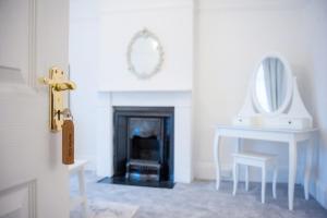 a room with a fireplace with a table and a mirror at The Mariners Suite in West Mersea