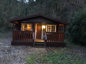 a small cabin with a porch in the woods at 3bears Log Cabin Whatstandwell Matlock Derbyshire in Crich