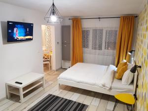 a small bedroom with a white bed and a tv at Dream Studio 2 Petrosani in Petroşani