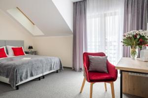 a bedroom with a bed and a red chair at Willa Mała Czyrna in Szczyrk