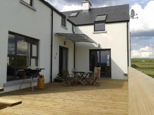 a white house with a patio with a table and chairs at Blackberry Lodge Accommodation in Doolin