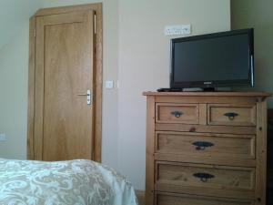 Schlafzimmer mit einem TV auf der Kommode in der Unterkunft Blackberry Lodge Accommodation in Doolin