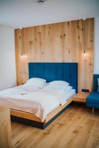 a bedroom with a large bed with a blue headboard at Der Kleine Bär in Hermagor