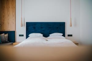 a bedroom with a large white bed with a blue headboard at Der Kleine Bär in Hermagor