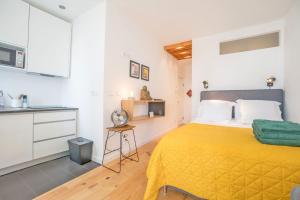 リスボンにあるDowntown Comfy Suiteのベッドルーム(黄色いベッド1台付)、キッチンが備わります。