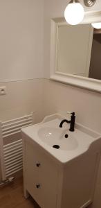 La salle de bains blanche est pourvue d'un lavabo et d'un miroir. dans l'établissement Panorama Apartmens Trenčín, à Trenčín
