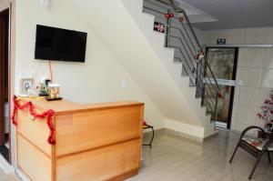 a living room with a tv and a staircase at Pousada Pouso Vitoria in Pirenópolis