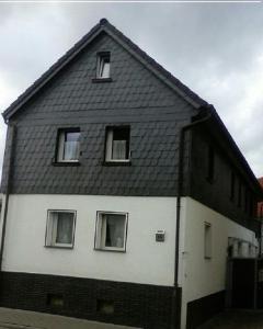 ein schwarzes und weißes Haus mit schwarzem Dach in der Unterkunft Ferienwohnungen Ober-Mörlen in Ober-Mörlen