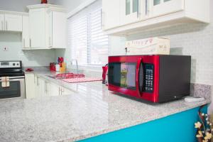 a red microwave sitting on top of a kitchen counter at Casa Victoria Golf Retreat in Caymanas