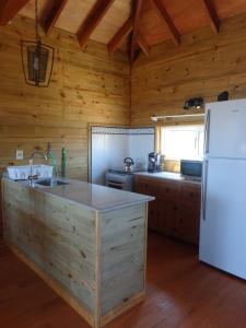 a kitchen with wooden walls and a white refrigerator at Emunah in Punta Del Diablo