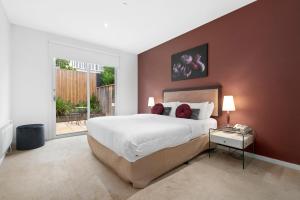 um quarto com uma cama grande e uma janela grande em Brighton Bay Apartments em Melbourne
