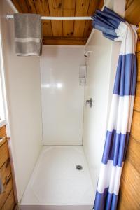 a shower with a blue and white shower curtain at Tatahi Cove Back Packer in Hahei
