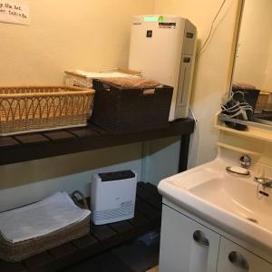 a bathroom with a sink and baskets and a refrigerator at Aigakusou in Nozawa Onsen