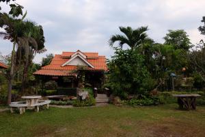 a house with an orange roof and benches in a yard at Sangsawang Resort in Mae Hong Son