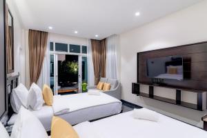 a hotel room with two beds and a flat screen tv at T Villas Hua Hin in Khao Tao